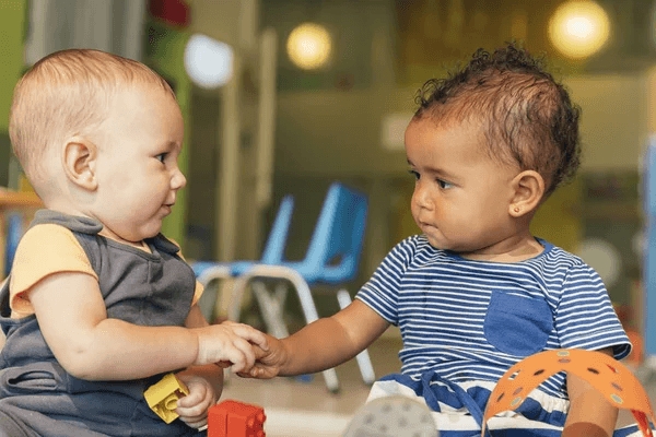 Deux bébés qui se regardent et se tiennent la main